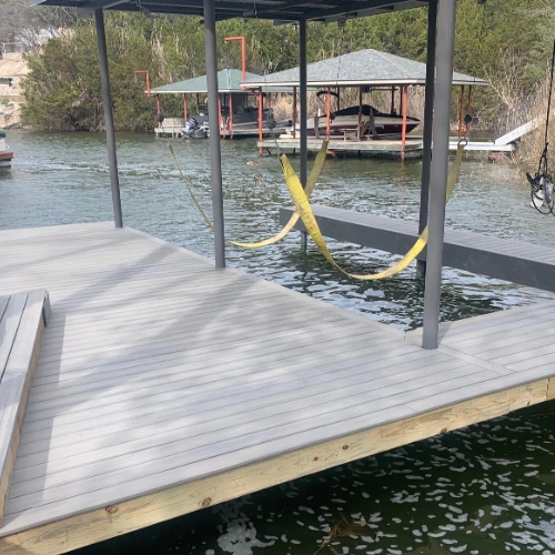 A completed Cozumel boat dock with a sleek, modern metal roof and a wooden deck. The dock is equipped with yellow boat lift straps and is positioned over calm waters, ready to accommodate a vessel.
