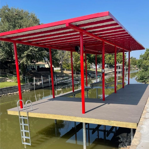A vibrant red steel-framed boat dock with a durable wooden deck, standing over a calm waterway. A ladder is attached to the side for easy access to and from the water, making this dock both functional and visually striking.