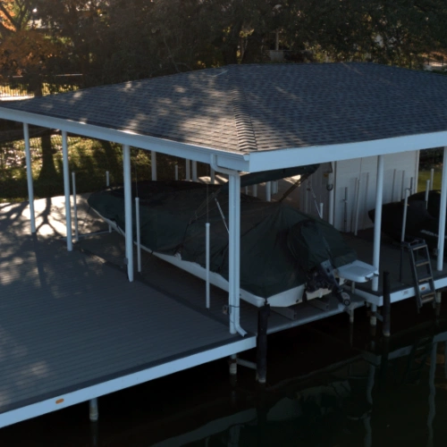 An aerial view of The Polynesian boat dock, showcasing its premium design with an expansive covered deck, two large boat slips, and integrated storage space. The dock is built with durable materials, ensuring long-term protection and functionality for ser