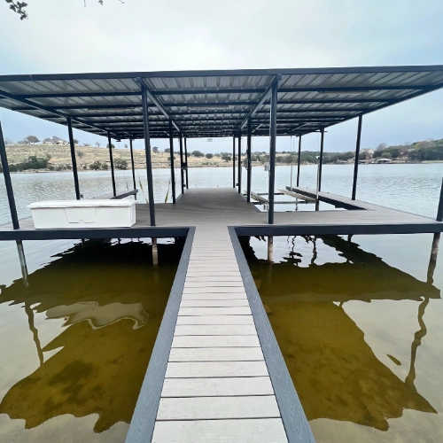 A newly installed dock with a sleek metal roof and reinforced decking, positioned on a quiet residential canal. The open and covered sections provide the perfect balance of shade and sun for a versatile waterfront experience.